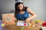 Girl showing how the Tender Leaf Toys wooden flower press works